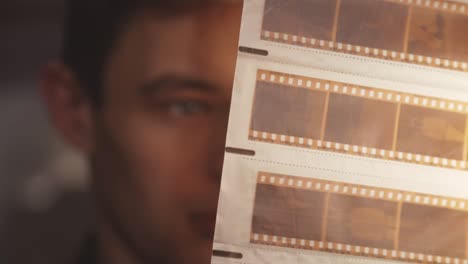 Man-Looking-At-Old-Vintage-Film-Negative-Strips