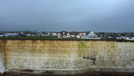 Cinematic-aerial-shot-Brighton-sea-wall-defences-and-chalk-cliff,-UK
