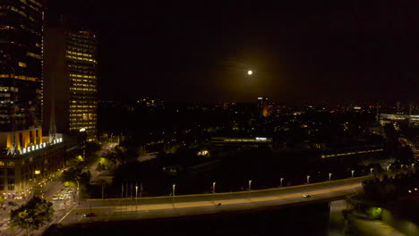 Full-moon-set-over-urban-train-tacks-with-bridge-arterial-crossing-in-the-foreground