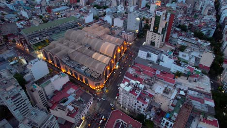 Aerial-view-dolly-in-establishing-of-the-Abasto-Shopping-mall-in-Almagro,-Buenos-Aires-city-at-night