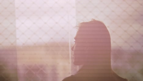 Silhouette-of-woman-looking-outside-apartment-window-in-the-morning,-slow-motion