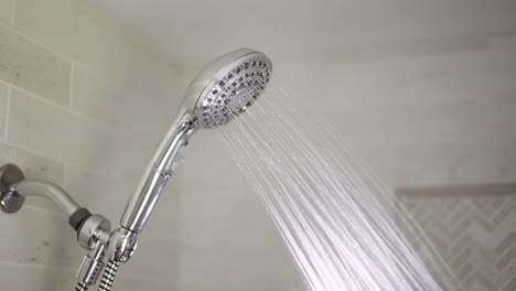 Chrome-shower-head-is-turned-on-where-hot-water-comes-out-and-then-turned-off-again