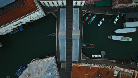 Vista-De-Arriba-Hacia-Abajo-Del-Puente-De-Rialto-Con-Barcos-Y-Góndolas-Que-Pasan-Por-Debajo-Del-Gran-Canal,-Venecia,-Italia---Disparo-De-Drones