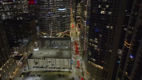 Aerial-overview-of-traffic-the-streets-of-night-lit-downtown-Houston,-US---reverse,-drone-shot