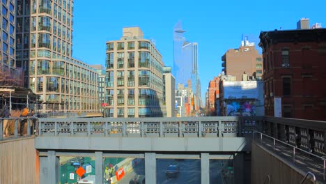 Shot-of-an-over-bridge-over-a-road-with-tall-buildings-visible-along-skyline-in-Manhattan,-New-York,-USA-at-daytime