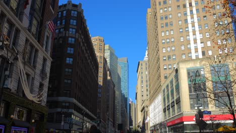 Low-angle-shot-of-New-York-skyline-on-both-sides-of-road-in-Manhattan,-New-York,-USA-at-daytime