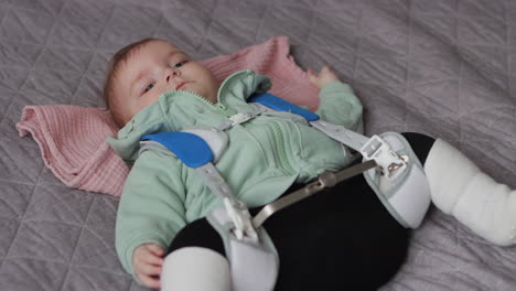 Baby-girl-lying-on-back-wearing-Pavlik-Harness-to-correct-Hip-Dysplasia