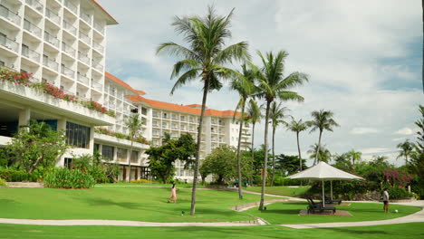 Hotel-Guests-Leisurely-Strolling-On-The-Lawn,-Enjoying-Warm-Sunshine-And-Tropical-Scenery-In-Cebu,-Philippines