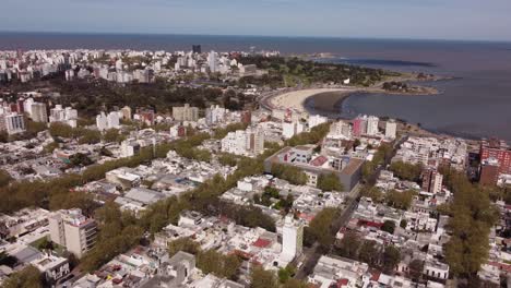 Aerial-panning-shot-of-Montevideo-City-with-sandy-beach-and-Ocean-during-sunny-day,Uruguay