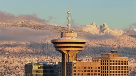 Vancouver-Harbour-Center-close-up-drone-aerial-shot-with-sunset-light-and-distant-snow-mountains