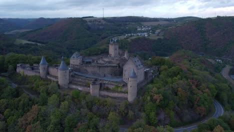 Castillo-De-Bourscheid-En-La-Cima-De-Una-Colina-Forestal-Con-Vista-Panorámica-En-Luxemburgo,-Antena