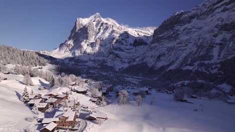 pushing-in-over-snow-covered-Chalets-at-Terrassenweg-towards-East-Side-of-Grindelwald-with-fabulous-views-of-Mount-Wetterhorn