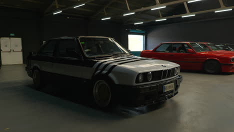 Cinematic-establishing-shot-of-parked-BMW-e30-in-indoor-exhibition-gathering