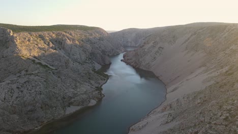Drone-cinematic-golden-hour-with-young-couple-stand-over-a-cliff-in-zrmanja-canyon,-Croatia
