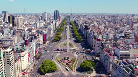 Aerial-view-establishing-9th-of-July-Avenue-with-a-path-of-trees-in-spring,-Obelisk-monument-in-downtown-Buenos-Aires,-Argentina