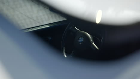 Close-up-of-interior-of-BMW-e30-car-steering-wheel,-white-exterior,-sliding