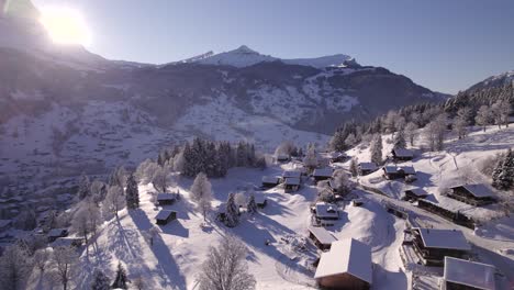 dolly-sideways-right-to-left-pushing-in-over-snow-covered-Chalets-in-Grindelwald-on-a-blue-bird-winter-day