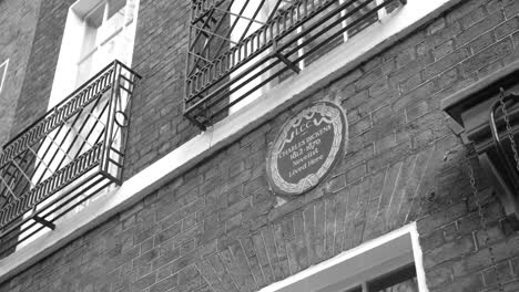 Monochrome-Shot-Of-Plaque-Commemorating-Novelist-Charles-Dickens-On-The-Exterior-Brick-Wall-Of-Charles-Dickens-Museum-In-London,-UK