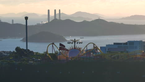 Aerial-orbiting-shot-of-Ocean-Park-in-Hong-Kong-and-Lamma-Island-power-station-in-background,-at-sunset