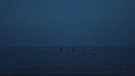 Zwei-Paddle-Boarder-Stehen-Vor-Der-Sonne-Im-Ruhigen,-Tiefblauen-Meer