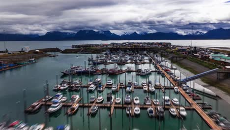 Aerial-drone-hyperlapse-timelapse-over-small-town-harbor-in-Homer-Alaska-at-sunset-with-fishing-boats-coming-in-and-out-of-marina-and-docking