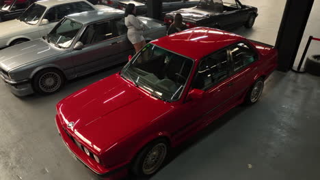 Classic-BMW-e30-car-parked-in-club-exhibition-warehouse-event,-orbiting-aerial-view-overhead