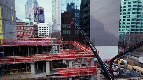 Aerial-view-around-red-knuckle-boom-cranes-at-a-construction-site-on-Jackson-Ave