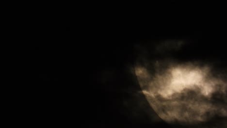 Illuminated-close-up-of-the-moon-in-the-dark-sky-with-clouds-passing-by