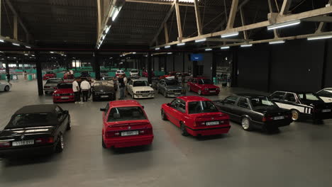 Aerial-view-of-indoor-BMW-e30-meet,-vintage-cars-in-bright-colors,-orbit