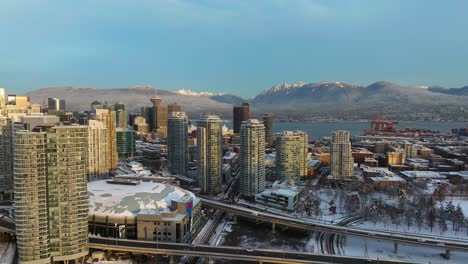Hermosa-Vista-Aérea-De-Los-Edificios-Comerciales-De-Vancouver-Cubiertos-De-Nieve-Y-Montañas-Nevadas-Lejanas