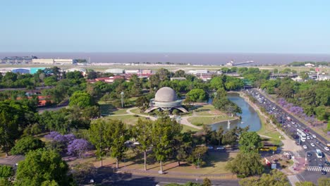 Aerial-dolly-in-view-of-Galileo-Galilei-planetarium-building-situated-in-a-park-with-a-pond-in-Buenos-Aires,-Argentina