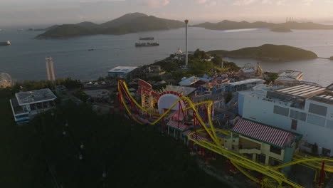 Rising-shot-of-Ocean-Park-amusement-park,-Hong-Kong,-with-container-ships-and-Lamma-Island-in-backdrop