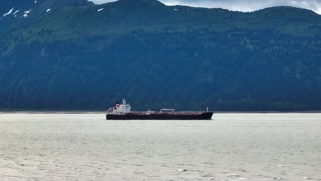 Cargo-ship-waiting-to-dock-in-Homer-Alaska-with-snow-capped-mountains-in-the-background