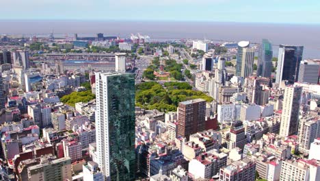 Aerial-view-establishing-dolly-in-of-Plaza-General-San-Martin-and-the-Torre-Monumental-in-the-Retiro-neighborhood,-port-in-the-background