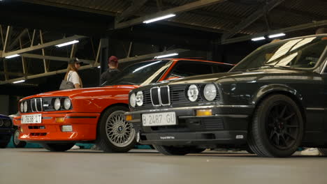 Close-up-view-of-BMW-E30s-on-display-at-a-car-show,-red-and-black-vehicles
