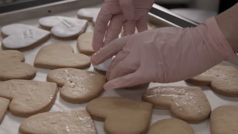 Woman-wearing-pink-gloves-decorating-butter-cookies-with-custom-made-icing-sheet,-4K-slow-motion