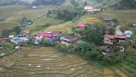 Aerial-of-an-asian-village-deep-in-the-exotic,-lush-and-green-mountains-of-Sapa-in-Vietnam
