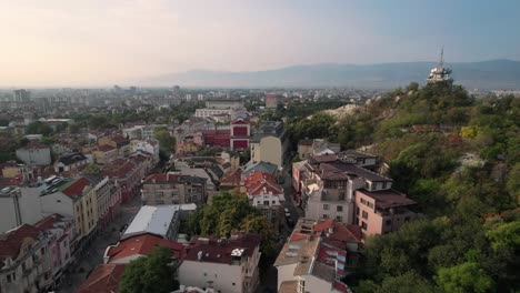 Scenic-aerial-drone-view-of-cityscape-of-Plovdiv-in-Bulgaria,-rising-above-hill