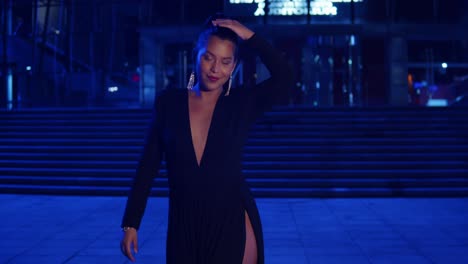 Young-woman-enjoying-the-city-at-night-in-a-black-dress-with-city-lights-in-the-background