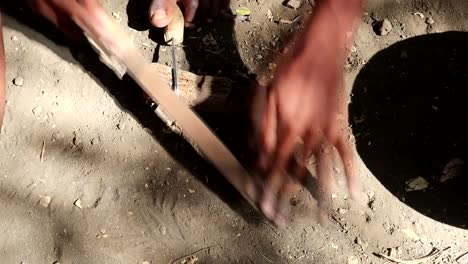 A-black-African-person-filing-a-tool-using-their-hands-and-feet