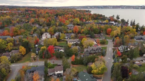 Iconic-town-hiding-in-autumn-color-tree-landscape,-aerial-drone-view