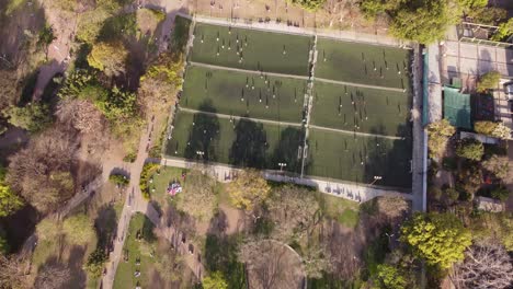 Aerial-top-down-flyover-football-fields-with-player-during-training-session-at-Las-Heras-Park-in-Buenos-Aires-City