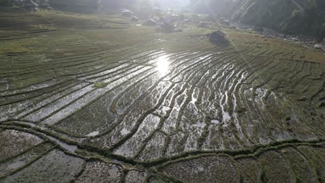 Stunning-aerial-shot-of-rice-fields-in-the-asian-mountains-with-the-sunlight-reflected-in-the-water