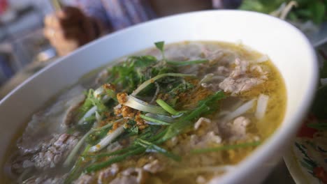 Woman-in-bikini-eating-traditional-vietnamese-pho-beef-noodle-soup-in-local-restaurant