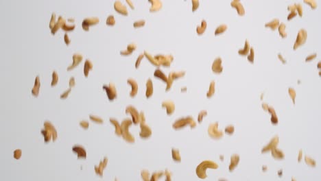 Roasted-and-salted-cashew-halves-falling-in-slow-motion-on-white-backdrop