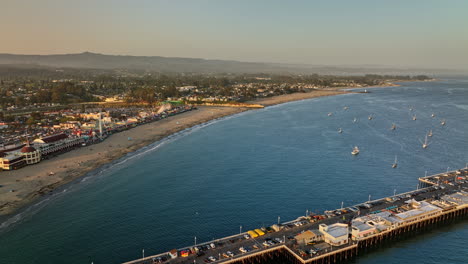 Santa-Cruz-California-Aerial-v11-cinematic-flyover-wharf-pier-panning-towards-popular-beach-boardwalk-entertainment-complex-and-outdoor-amusement-park-at-sunset---Shot-with-Mavic-3-Cine---May-2022
