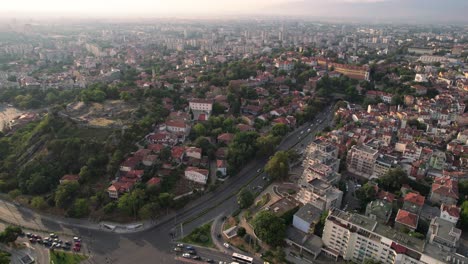 Plovdiv-cityscape-landscape,-aerial-drone-flying-above-busy-road-to-archeological-site-over-hill