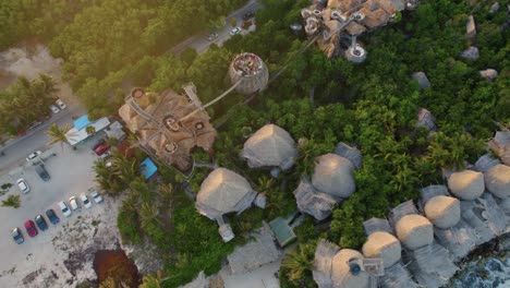 Aerial-top-view-of-Azulik-Resort-in-Tulum-Mexico-in-the-magical-golden-light-of-sunset,-slow-rising-up-with-tilt-down-drone-shot