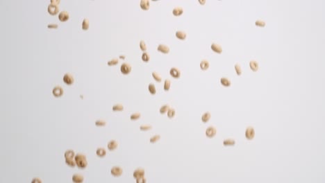 Cheerios-cereal-raining-down-on-white-backdrop-in-slow-motion