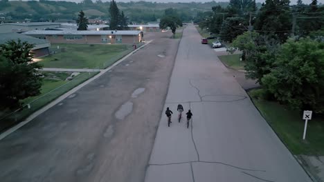 Tres-Niños-Pequeños-Andan-En-Bicicleta-Por-Una-Bonita-Zona-Urbana-Durante-La-Puesta-De-Sol